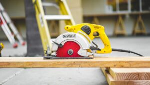 yellow table saw on piece of wood